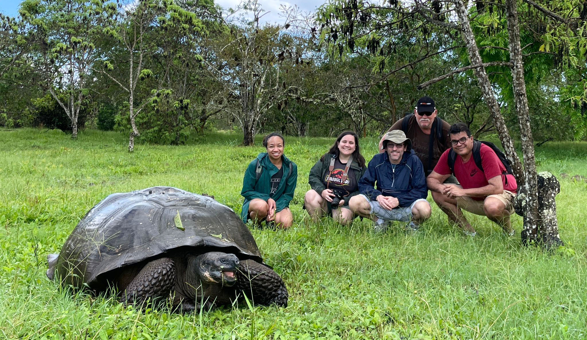 Galápagos Islands team photo posing with a giant tortoise