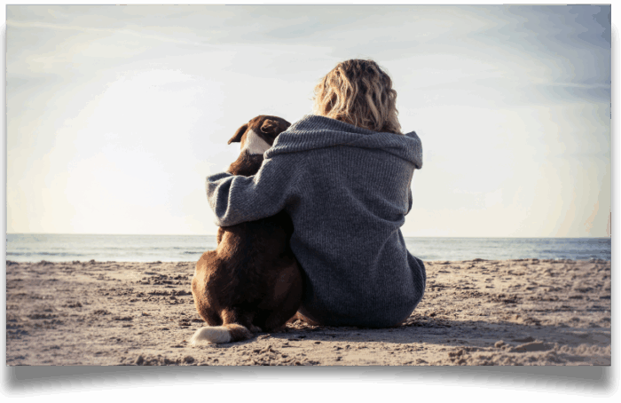 Woman hugging dog on the beach